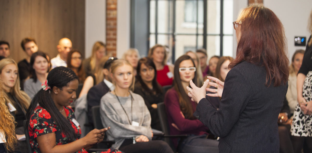 Woman speaking to a crowd at a salon, Diversity in Tech