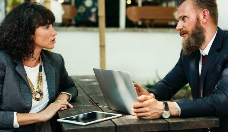 man and woman talkign together while using computer