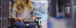 Young woman in wheelchair looking up for book in library and need inclusive design