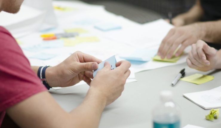 Person at an office desk writing on a post-it note