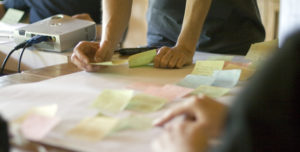People working at a desk with post it notes and planning user story journeys