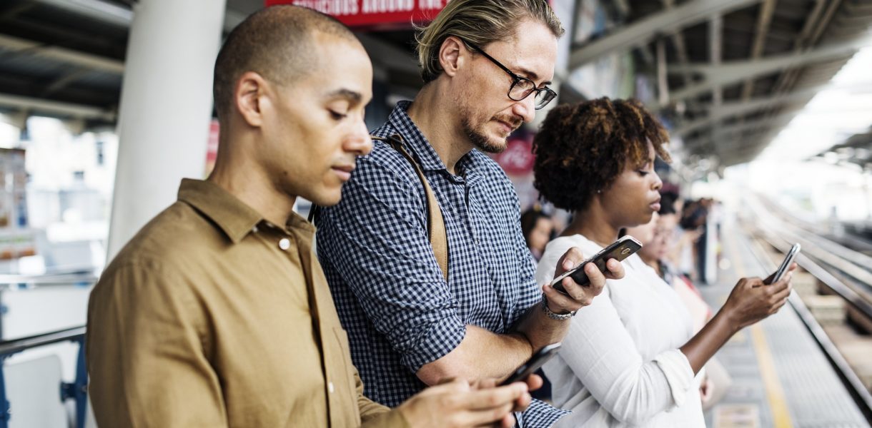 3 people at a train station on their phones