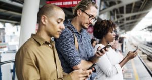 3 people at a train station on their phones
