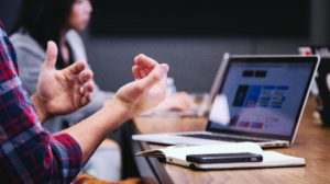 Person gesturing with their hands, whilst using a laptop