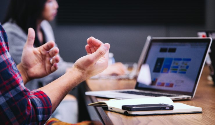 Person gesturing with their hands, whilst using a laptop