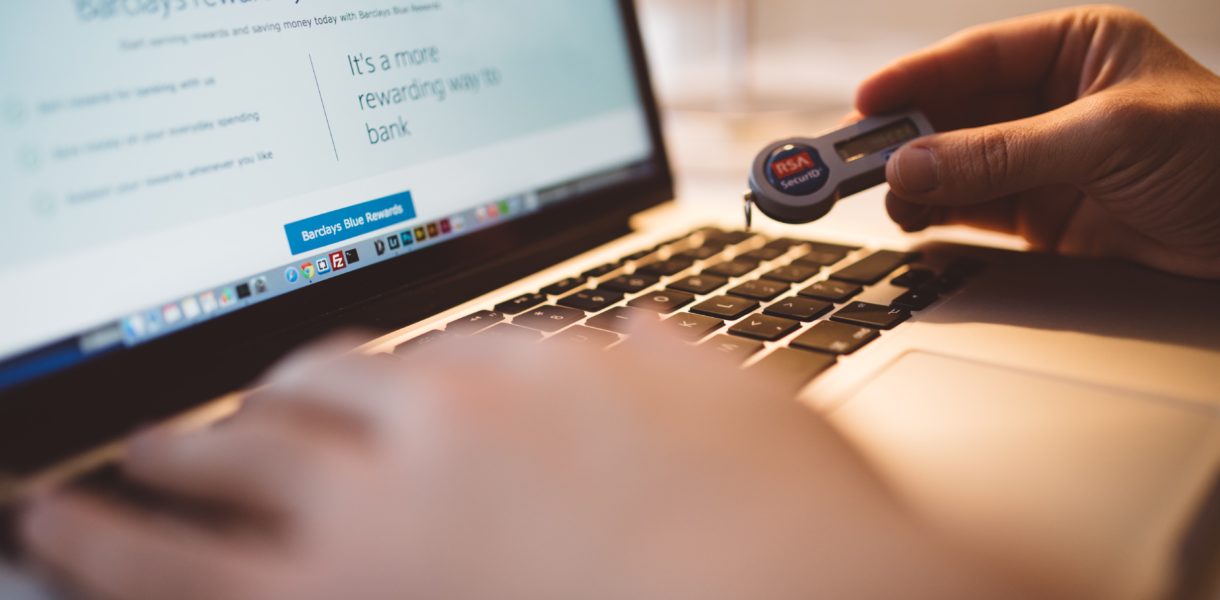 Someone typing at a keyboard whilst holding a security ID fob