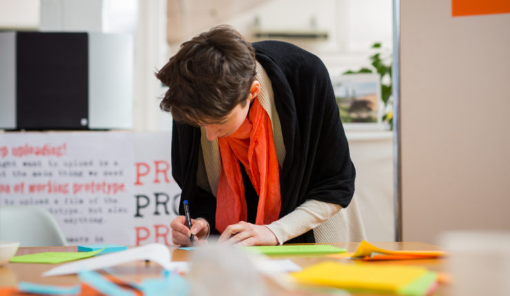 Woman leaning over a table of post-it notes, going through a service design process
