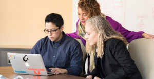 3 women around a laptop increasing their digital skillset and training