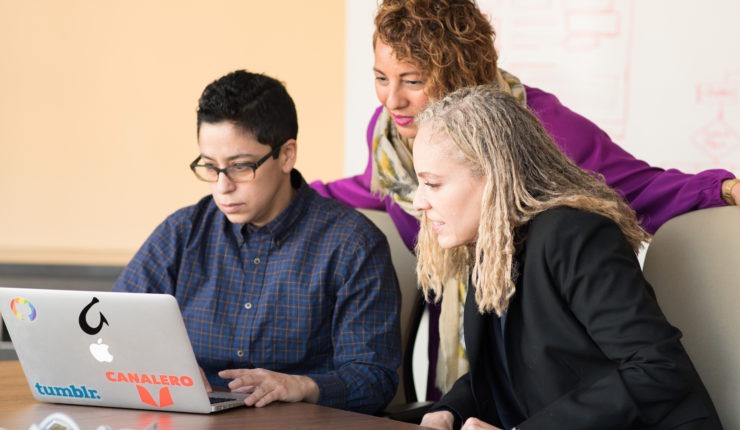 3 women around a laptop increasing their digital skillset and training