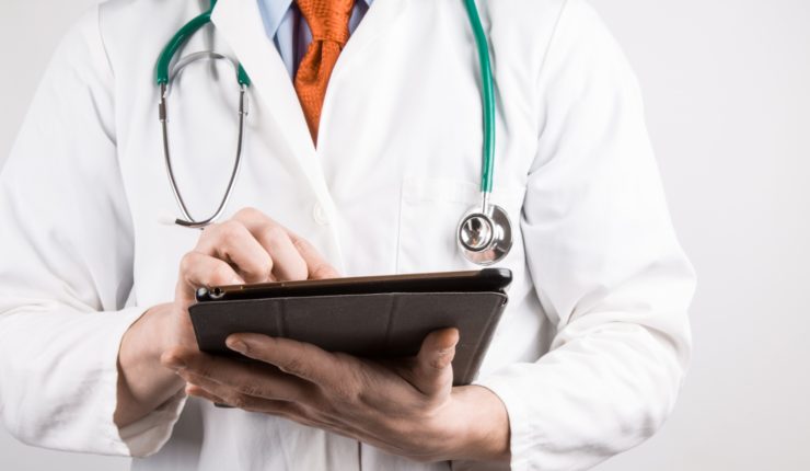 Doctor using a tablet to update the cloud healthcare software data