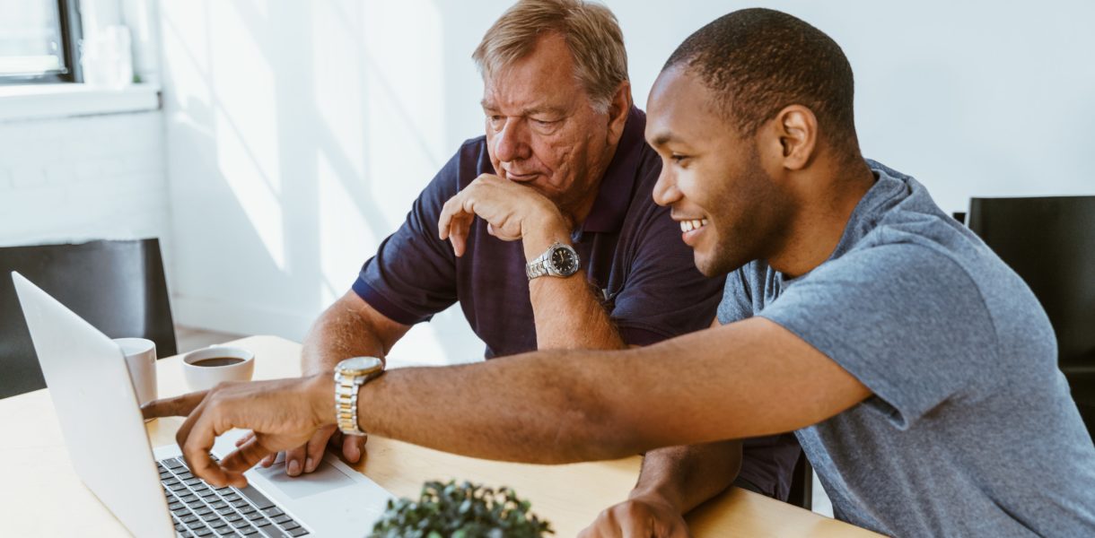 man helping a senior citizen use a computer