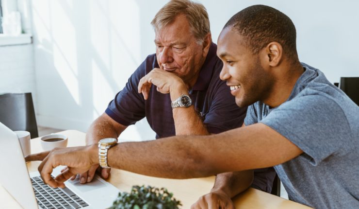 man helping a senior citizen use a computer