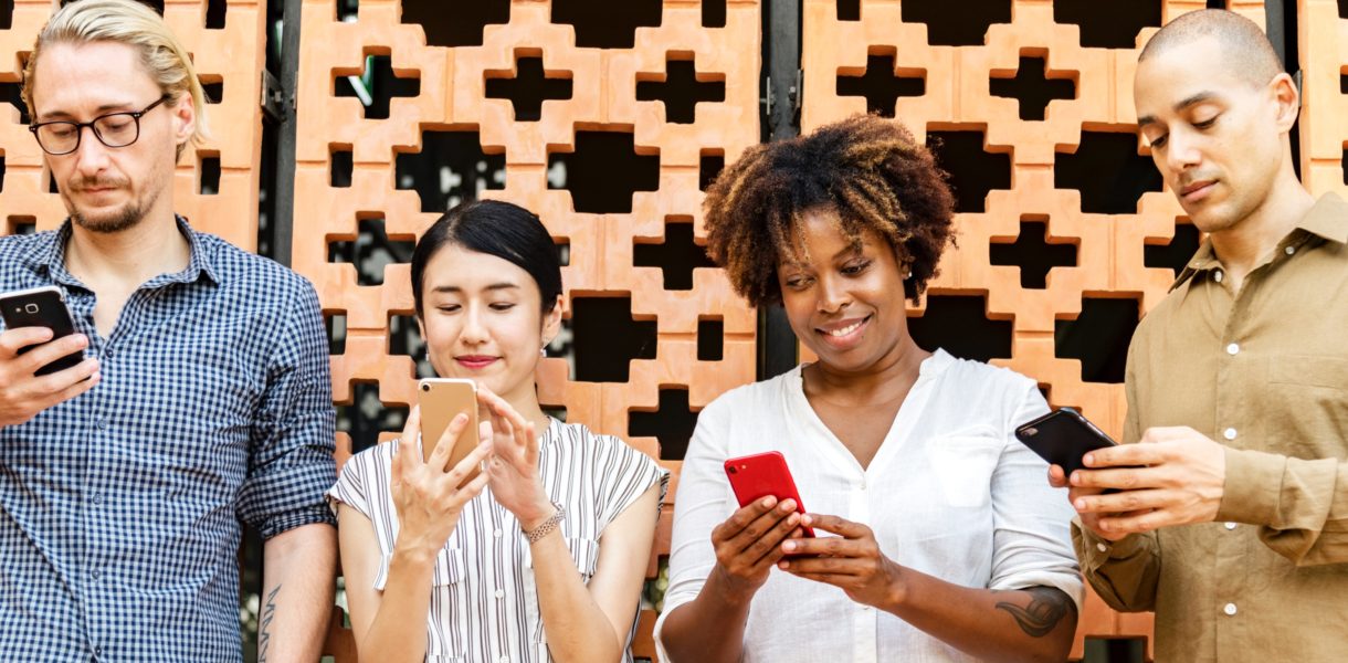 4 people in a line using their phones on social media platforms