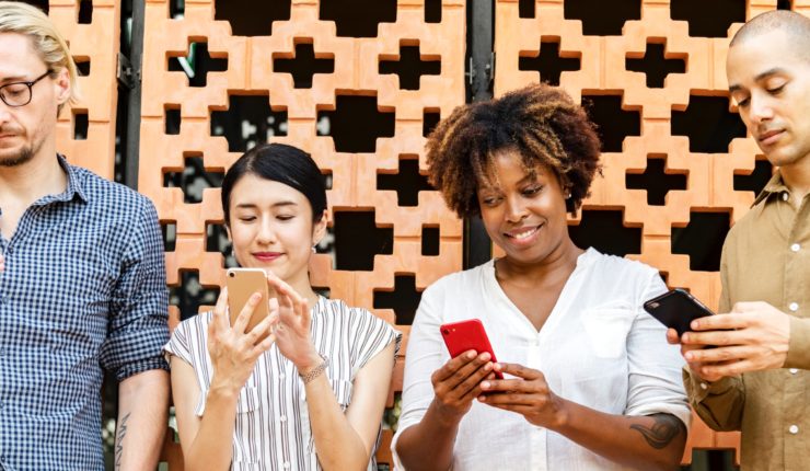 4 people in a line using their phones on social media platforms