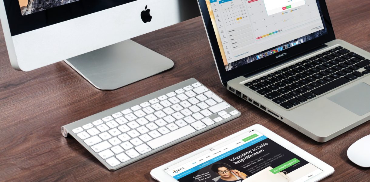 A group of apple products, including an iMac, macbook, ipad and wireless mouse