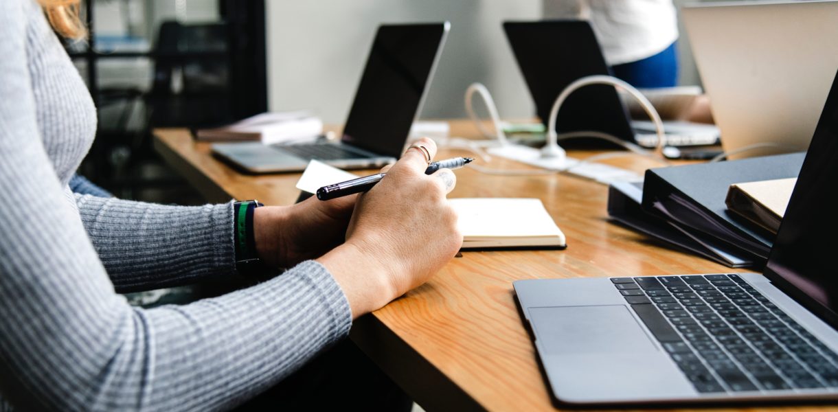 Woman sat around a table in a business meeting with a macbook air