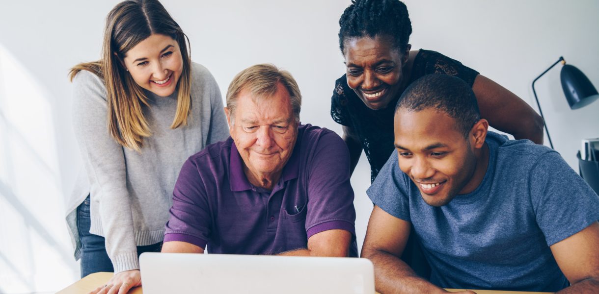 Diverse group of people looking at a computer
