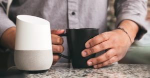 man holding a coffee next to a smart home device