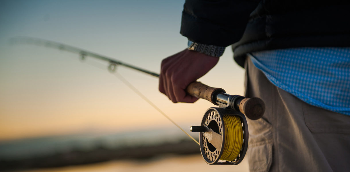 Sunrise over the marsh with man holding a fly rod and reel