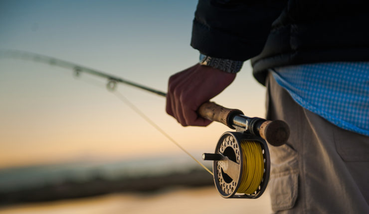Sunrise over the marsh with man holding a fly rod and reel
