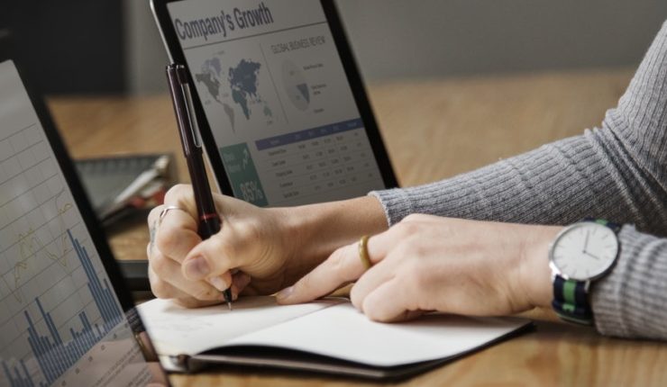 hands in a notebook in between two laptops