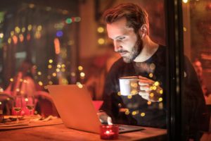man working on computer while drinking coffee