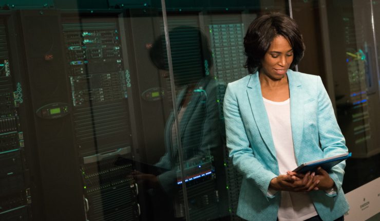 Woman reading tablet in front of giant computer