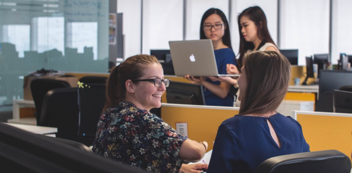 women in office space talking and working on computers
