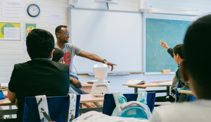 Man teaching a youth class using a robot