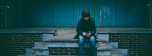 young boy using phone, sitting outside