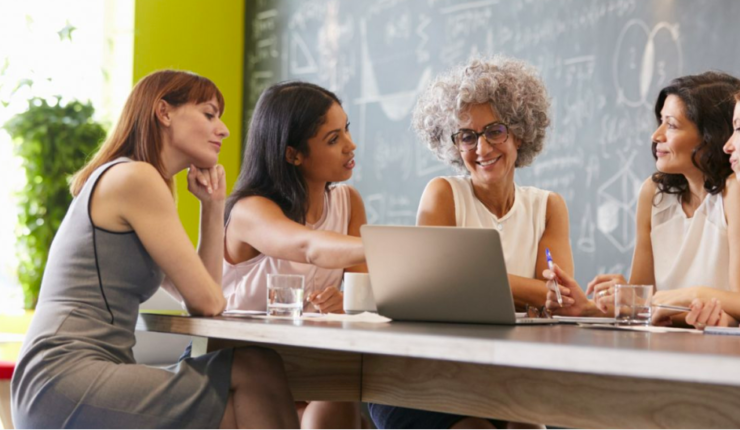 women sitting at table working on computer