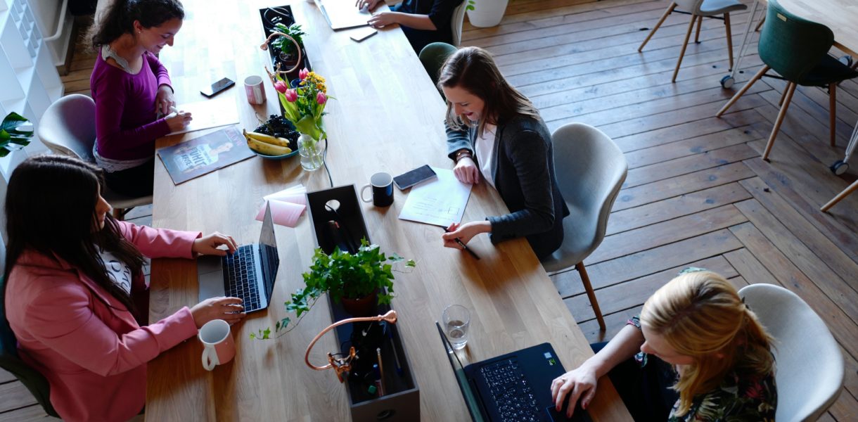 group on women working on computers at a large desk
