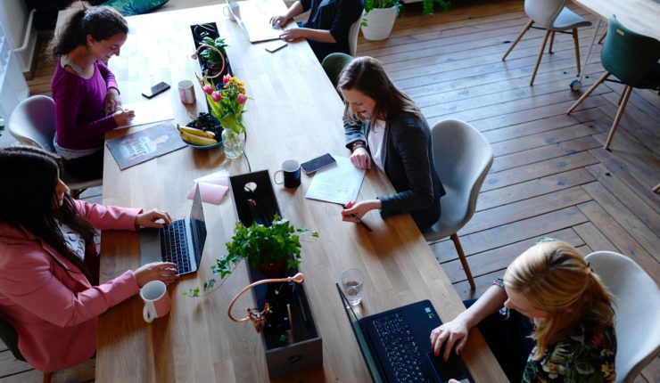 group on women working on computers at a large desk