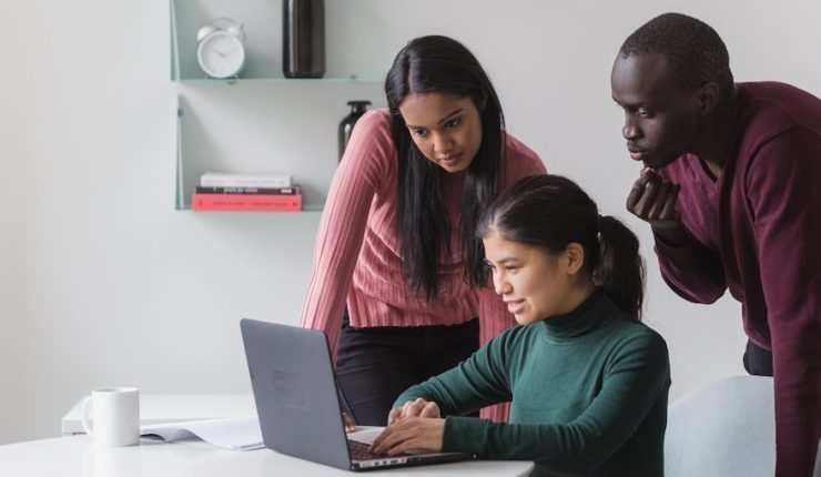 Three people around laptop