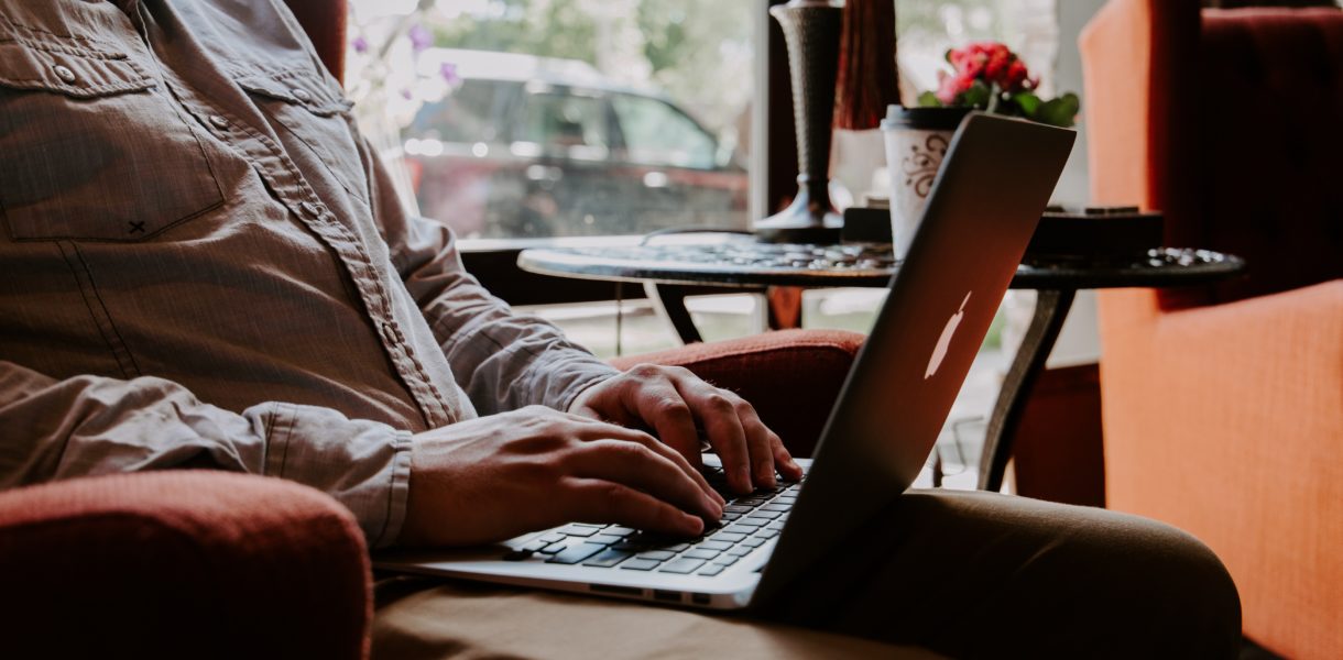man sitting in chair typing on computer