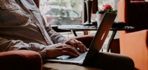 man sitting in chair typing on computer