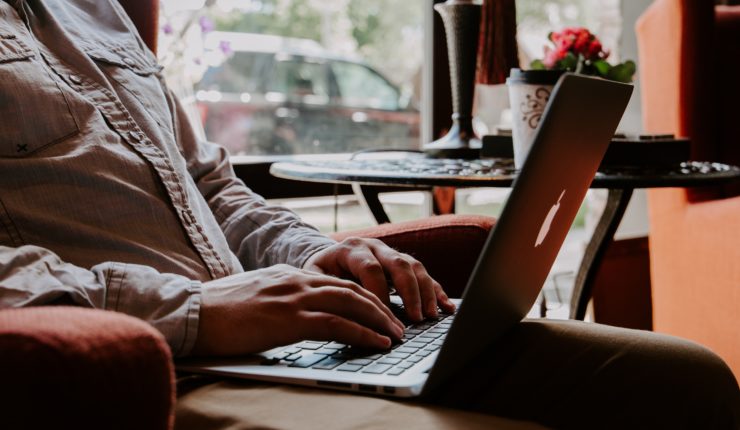 man sitting in chair typing on computer