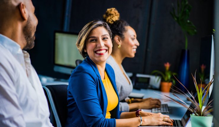 two women and a man sitting with computers