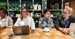 adults sitting at table with computers