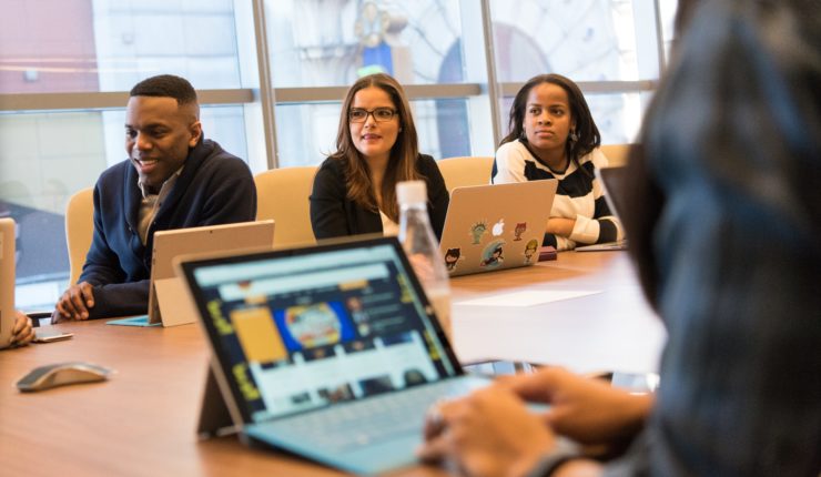adults sitting at table with computers