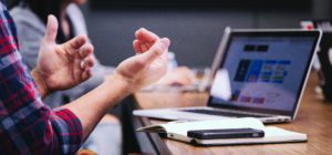 person sitting at table explaining, while using his hands