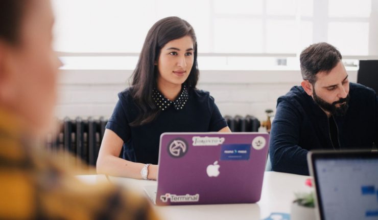 people sitting at meeting table with computers