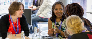 women sitting around a table talking and working