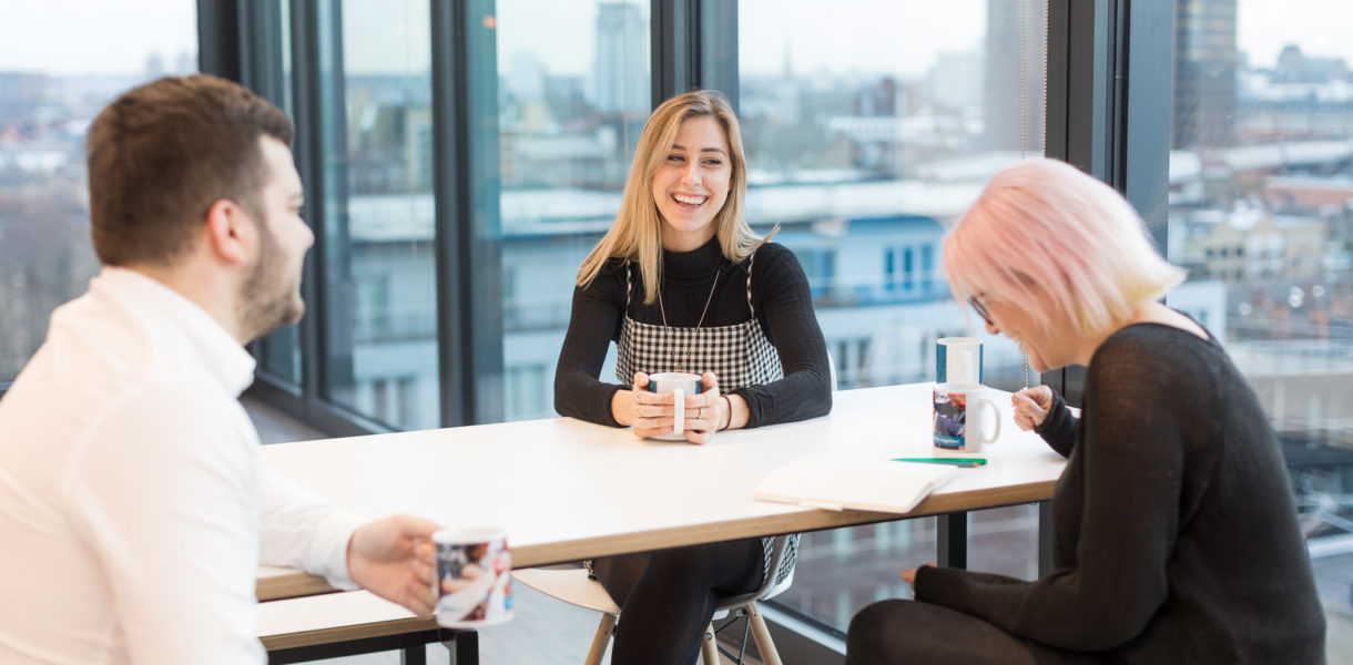people sitting a table at work talking and laughing