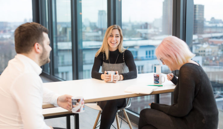 people sitting a table at work talking and laughing