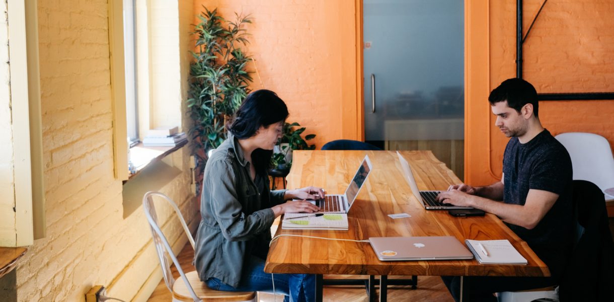 woman and man working on their computers at large desk