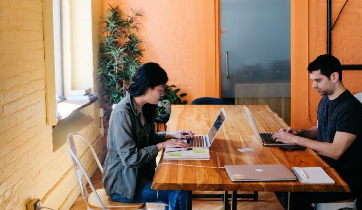 woman and man working on their computers at large desk