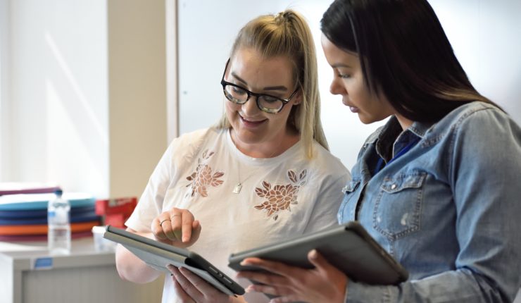 two women looking at tablets