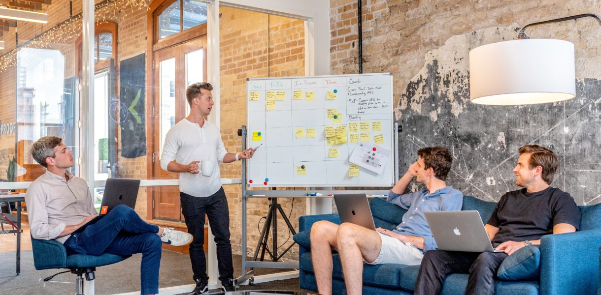 group of men discussing and taking notes on whiteboard