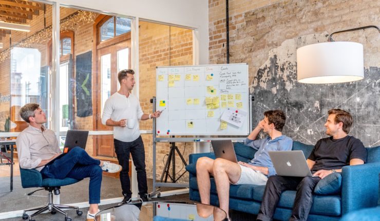 group of men discussing and taking notes on whiteboard
